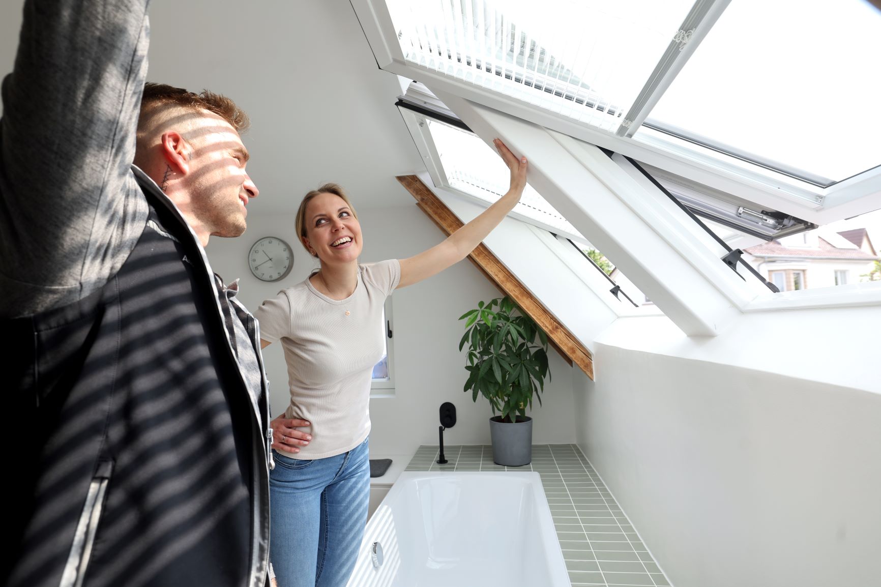 Ein Servicetechniker und eine Kundin betrachten gemeinsam ein geöffnetes Dachfenster.