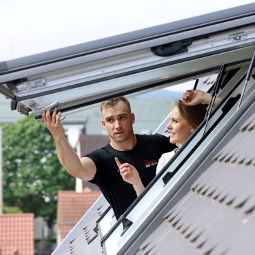Kundin und Servicetechniker am offenen Dachfenster Kundin und Servicetechniker am offenen Dachfenster