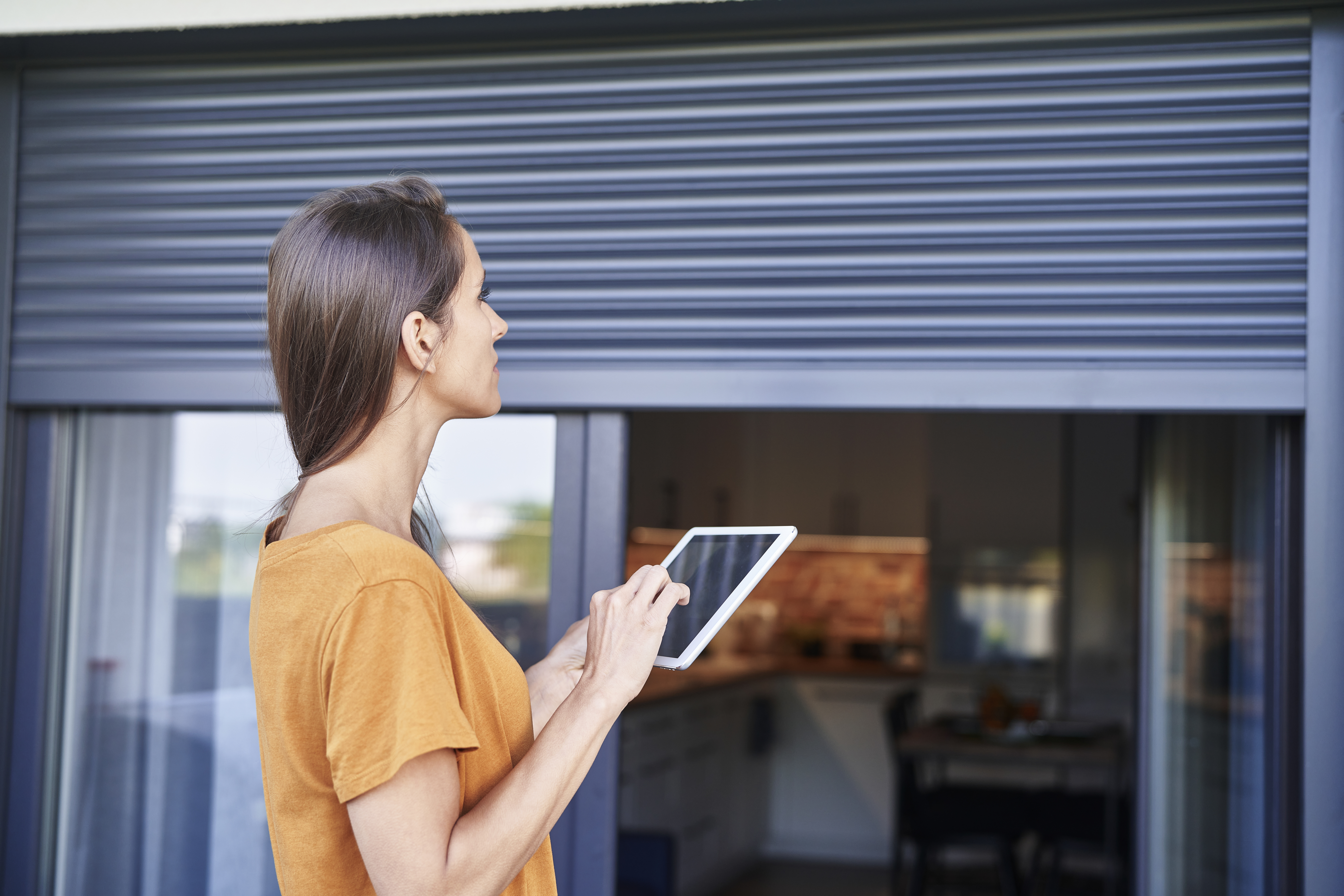 Freu steuert Rollladen an Fenster-Türen Fassade mit Tablet