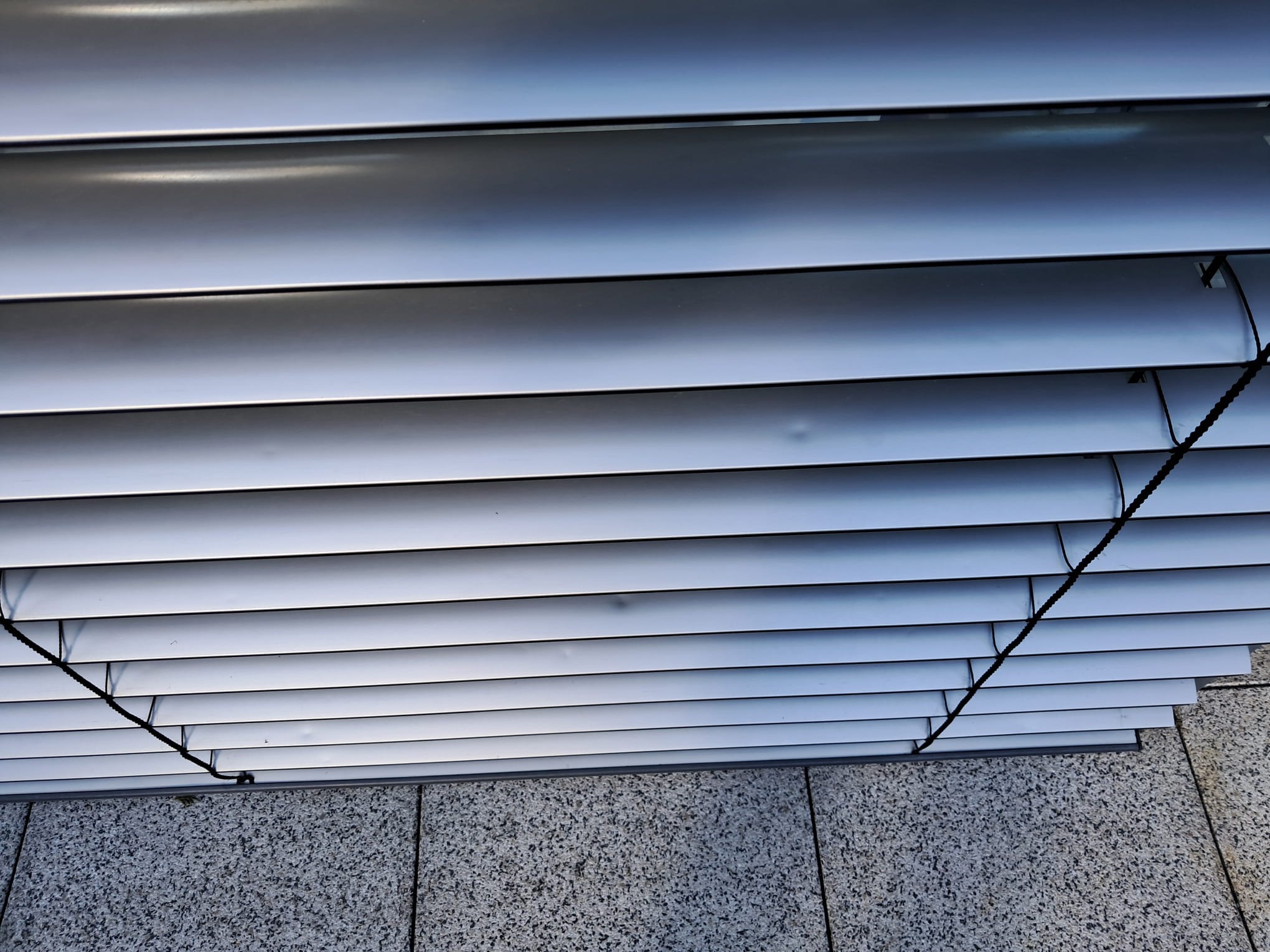 Hagelschaden am Raffstore Behang eines Fassadenfensters Hagelschaden am Raffstore Behang eines Fassadenfensters