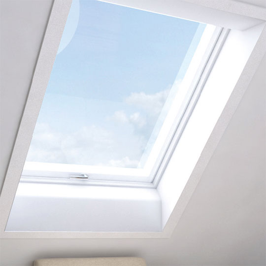 Ein geschlossenes Dachfenster, das in eine weiße Decke eingebaut ist. Das Innenfutter der Dachfensters ist angeschrägt.