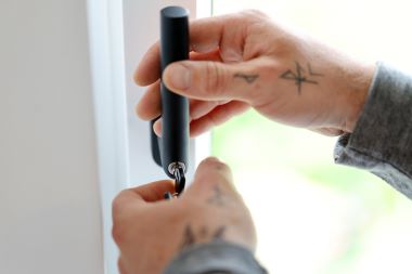 Ein Service-Techniker installiert ein Sicherheitsschloss an einem Fenster.
